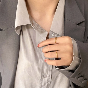 Bagues dorées géométriques minimalistes portées avec un blazer gris très élégant