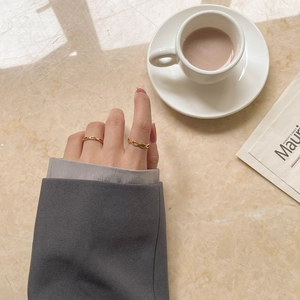 Détail de bagues dorées ondulées et minimalistes sur la main du mannequin sur marbre