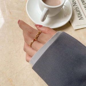 Bague infinity dorée minimaliste portée au doigt dans un cadre de vie élégant
