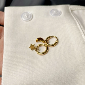 Boucles d'oreilles asymétriques dorées étoile et lune sur une manchette de chemise