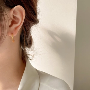 Vue détaillée de la boucle d'oreille étoile dorée portée sur le modèle montrant l'éclat