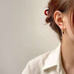Gros plan sur une boucle d'oreille anneau lune dorée avec accessoire de pince à cheveux