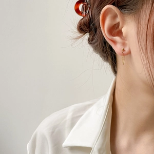 Close-up of elegant gold chain tassel earrings on model showing stylish drop design