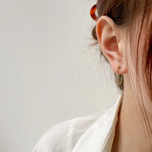 Detail of elegant gold chain earrings with ball stud and fringe design on a model