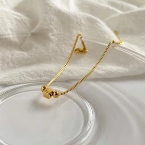 Detail of gold cube and round beads on a square link titanium steel bracelet
