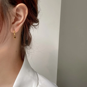 Gros plan d'une boucle d'oreille étoile dorée portée par un mannequin, style minimaliste