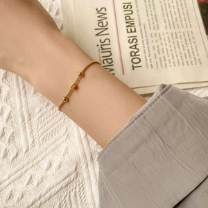 Detail view of a gold square charm and beads on a sleek box chain bracelet for women