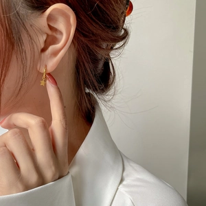Boucles d'oreilles asymétriques en or avec étoile et lune portées par un mannequin
