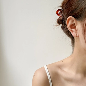 Detail of gold bar drop earrings and brown tortoiseshell resin hair clip worn by a model