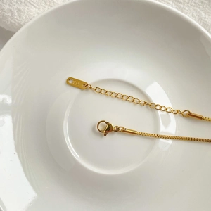 Detailed macro view of 18K gold box chain with lobster clasp and K18 engraving