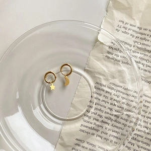 Détail des boucles d'oreilles créoles asymétriques étoile et lune en or brillant