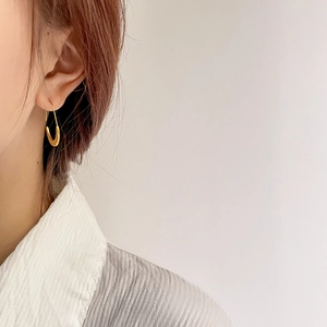 Close-up of a model wearing minimalist gold U-shaped hoop earrings with a polished finish