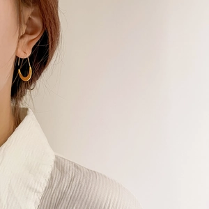 Detail view of a French style golden U-shaped earring on ear with sleek geometric design