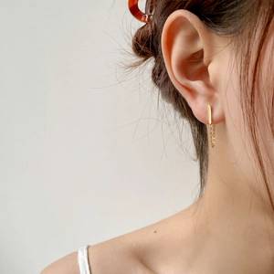 Detail of gold chain tassel earring on model, minimalist drop style for women
