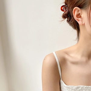 Detail of gold chain tassel earrings and amber claw clip worn on a model in white lace