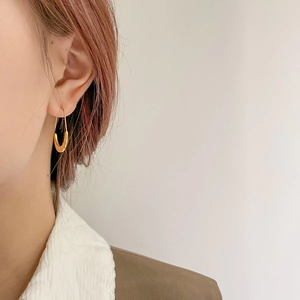 Close-up of elegant gold U-shaped oval hoop earrings worn on a model with soft lighting