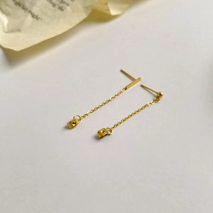 Detailed macro view of gold tassel earrings with long chains and small geometric cubes