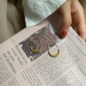 Detail of gold crescent hoop earrings with a matte texture on a vintage paper background