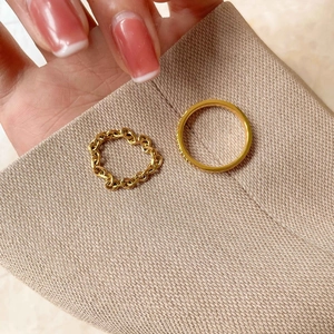 Macro detail of gold-plated braided chain ring and minimalist smooth band set