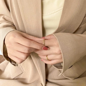 Golden braided chain ring and slim textured band set worn on a model's hand