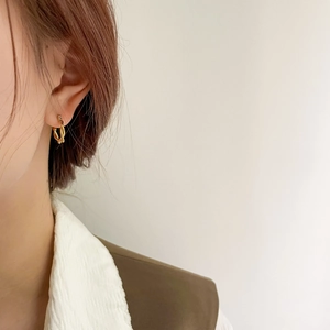 Close-up of gold twisted rope hoop earrings worn on ear with minimalist style
