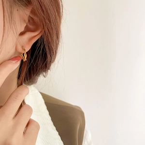 Close-up of minimalist golden twisted hoop earrings with delicate braided metal texture