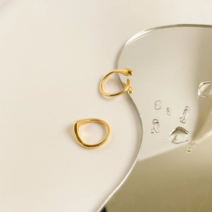 Detailed view of 15k gold plated geometric rings on a mirror surface with water drops