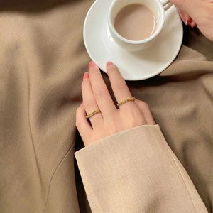 Golden twisted chain ring set on fingers with elegant brown blazer background
