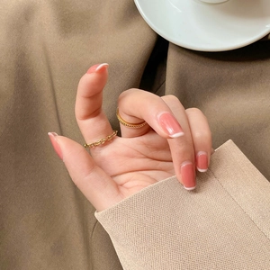 Close-up of golden braided chain rings paired with elegant French tip gradient nails