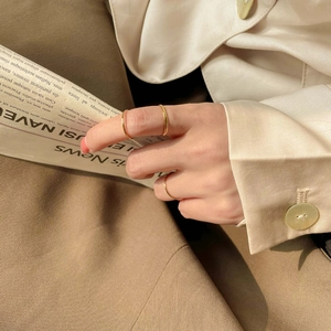 Three minimalist gold-plated stacking rings shown on a model with a stylish background