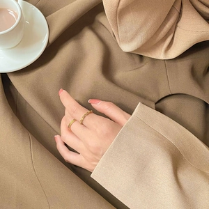 Detail of gold twisted rope ring and minimalist slim band set on an elegant fabric background