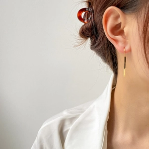 Close-up of elegant long gold bar drop earrings on model with high-shine polished finish