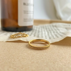Detail showing the intricate gold rope texture on the minimalist metallic ring surface