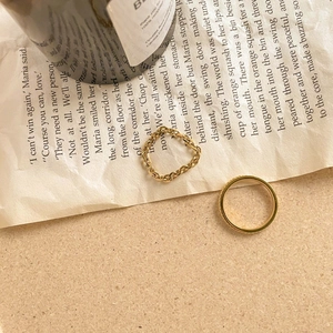 Detailed view of gold chain link ring and minimalist textured band on vintage background