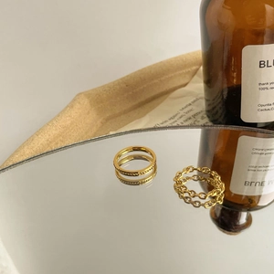Detailed close-up of golden braided twist and hollow chain rings on a vintage mirror