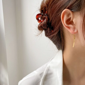 Minimalist long gold twisted drop earrings shown on model with hair claw clip