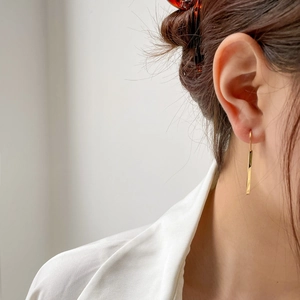Elegant gold twisted bar drop earrings for women worn by a model in a minimalist style