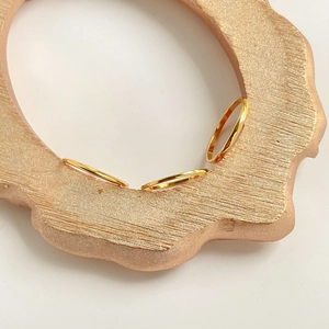 Detailed close-up of three minimalist polished gold rings on a textured rose gold surface