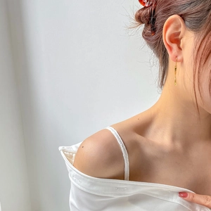 Minimalist gold twisted long bar drop earrings on female model with soft lighting