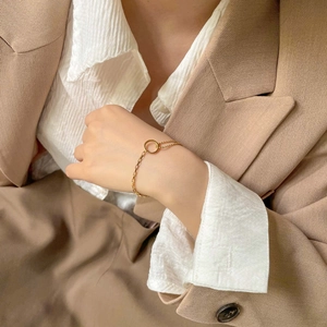 Gros plan d'un bracelet doré asymétrique à cercle creux sur le poignet du mannequin