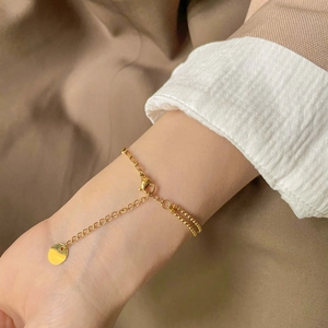 Bracelet double chaîne dorée avec pendentif rond évidé et design géométrique épuré