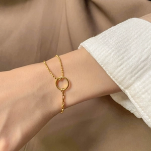 Détail d'un bracelet géométrique asymétrique doré avec maillons de billes et de boîtes