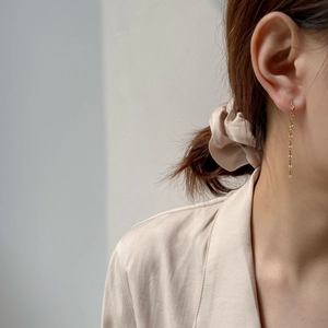 Detail view of 18K gold long tassel chain earrings showing elegant drape on model