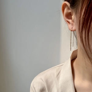 Close-up of elegant long gold chain tassel earrings worn on a model's ear