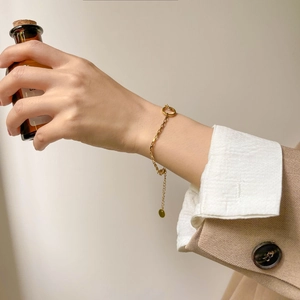Détail d'un bracelet géométrique doré minimaliste avec chaîne réglable sur le poignet du mannequin
