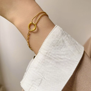 Gros plan détaillé d'un bracelet doré asymétrique avec perles et maillons rectangulaires