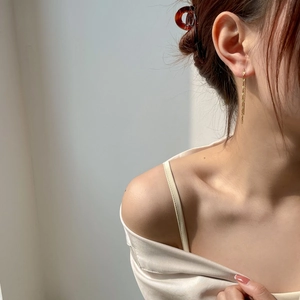 Detail of elegant gold tassel drop earrings showing minimalist chain draping style
