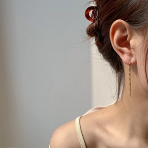 Close-up of elegant long gold tassel chain earrings worn by a model in soft light