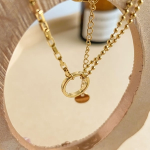 Collier doré multi-rangs avec anneaux géométriques creux et breloques sur chaînes variées