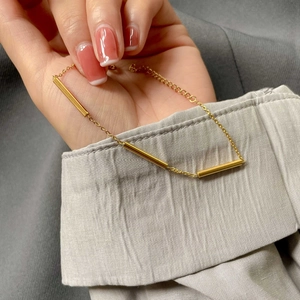 Minimalist gold cylindrical tube bracelet with high-polish finish on a female wrist